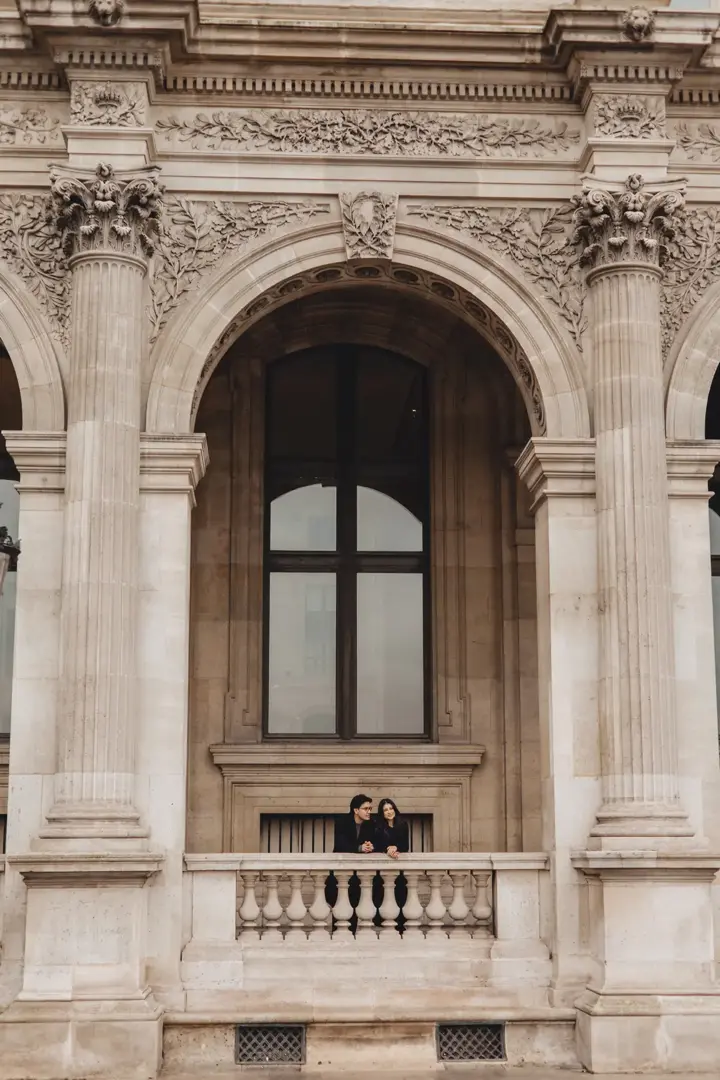 Couple Louvre museum arch balcony Paris architecture