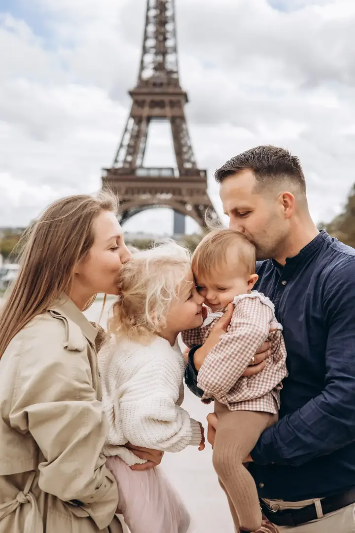 Parents kissing children Eiffel Tower Paris family